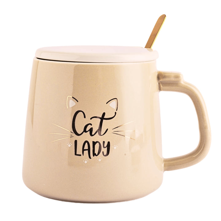 A ceramic mug with a cute cartoon cat printed on the side. The mug is a brown color and has a white ceramic lid.. A golden spoon sits beside the mug.