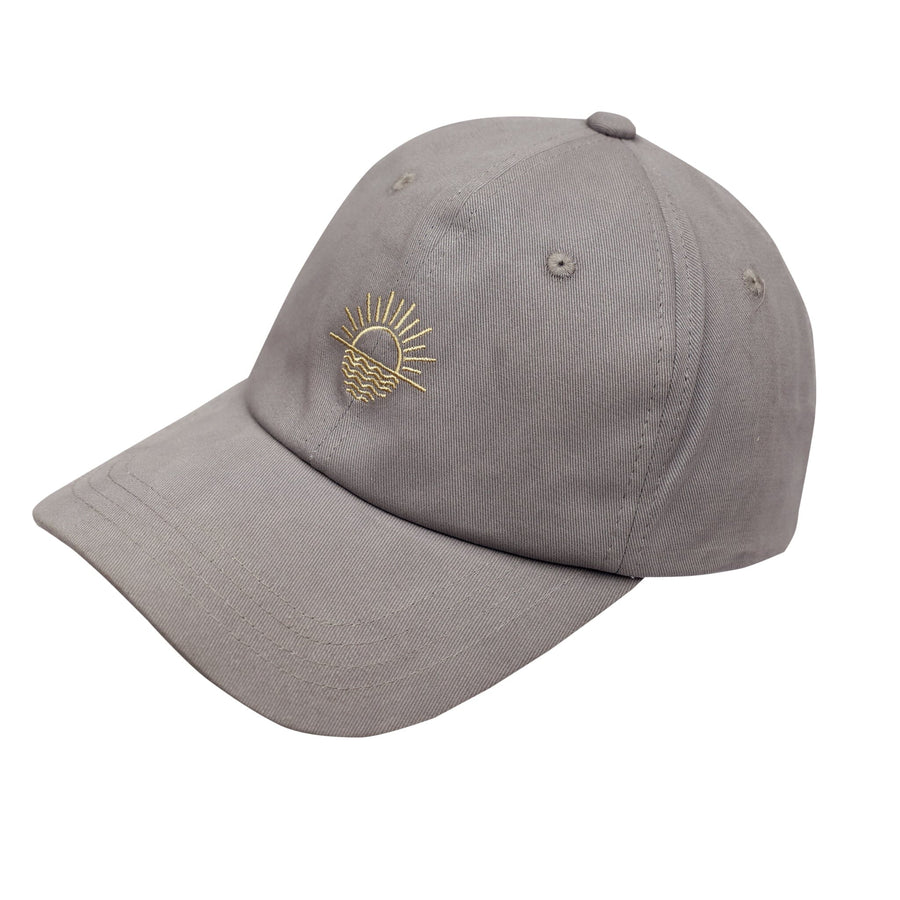 A white cotton baseball cap with a curved brim and an adjustable strap in the back. The front of the cap has a colorful rising sun embroidered on it.