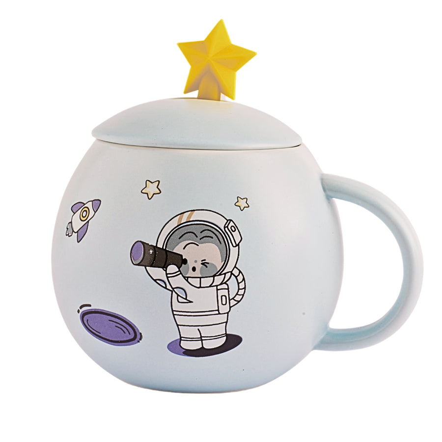 A ceramic mug with a cartoon astronaut and planets printed on the side. The mug is a light blue color and has a white ceramic lid with a small handle on top.