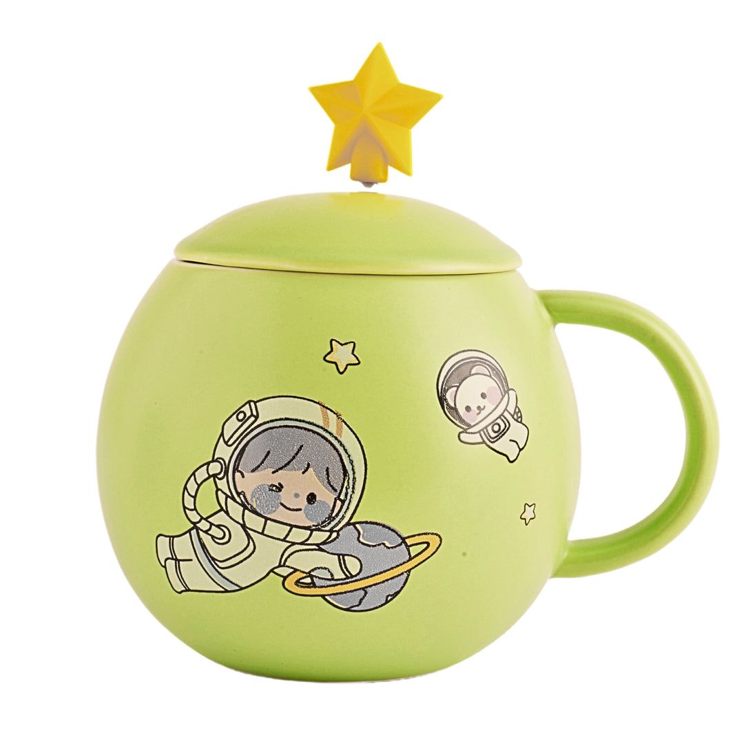 A ceramic mug with a cartoon astronaut and planets printed on the side. The mug is a light green color and has a white ceramic lid with a small handle on top.