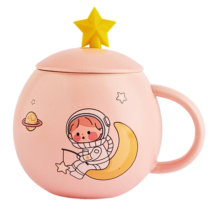 A ceramic mug with a cartoon astronaut and planets printed on the side. The mug is of pink color and has a white ceramic lid with a small handle on top.